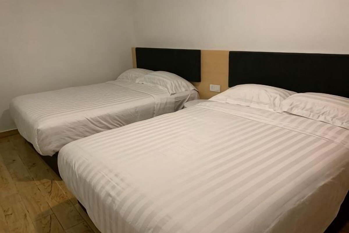 Two single beds with headboards, a wooden floor, and a plain wall.