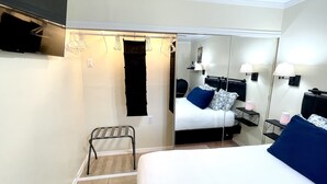 Habitación de hotel con cama, una silla, un espejo y televisión.