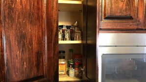Cocina con armarios de madera, un microondas y diversos utensilios de cocina en las repisas.