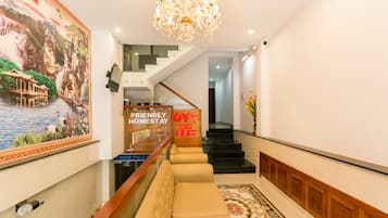 Een hotel lobby met een trap, een receptiebalie, een zithoek en een kroonluchter.