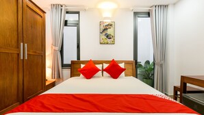 Habitación de hotel con una cama grande, armario de madera y una planta en maceta.