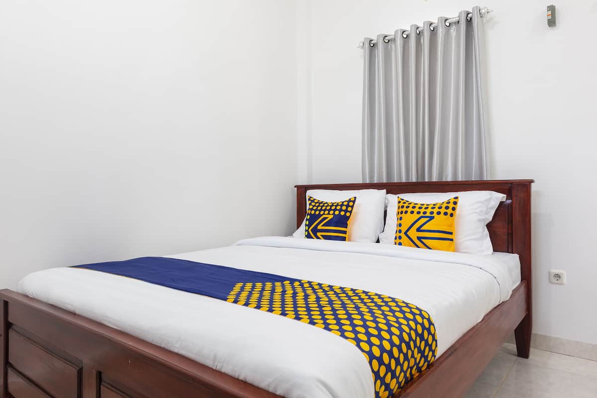 A neatly made bed with a blue and yellow patterned bedspread, white pillows, and a wooden headboard.