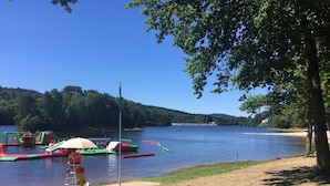 A lakeside area with a sandy beach, a row of colorful floating docks, and a bench under a tree. - Romantic French country barn perfect for a couple/weekend breaks. (Gourdon-Murat)