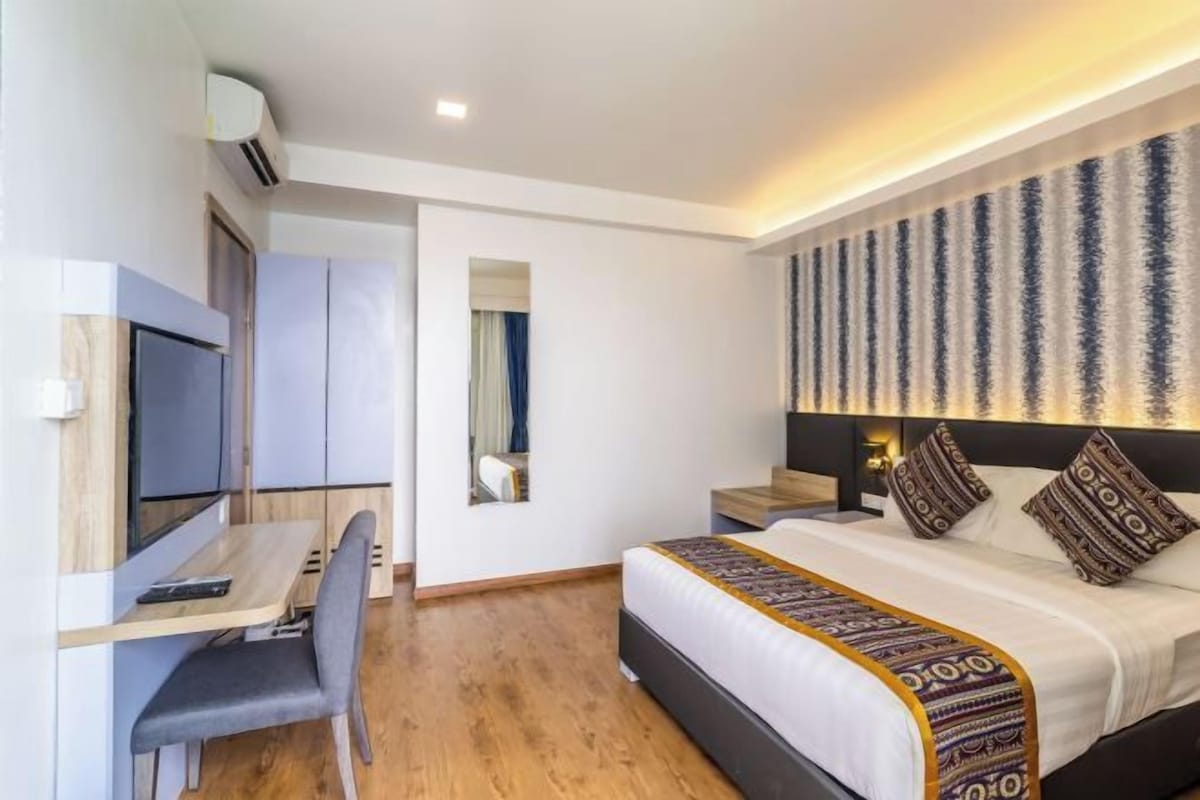 A modern hotel room with a bed, a desk, and a television.