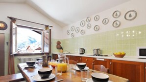 Una cocina con una mesa de madera dispuesta para el desayuno, una ventana con vistas y una pared decorada con cuadros.