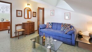 Una sala de estar con un sofá azul, una mesa de centro de vidrio y un aparador de madera.