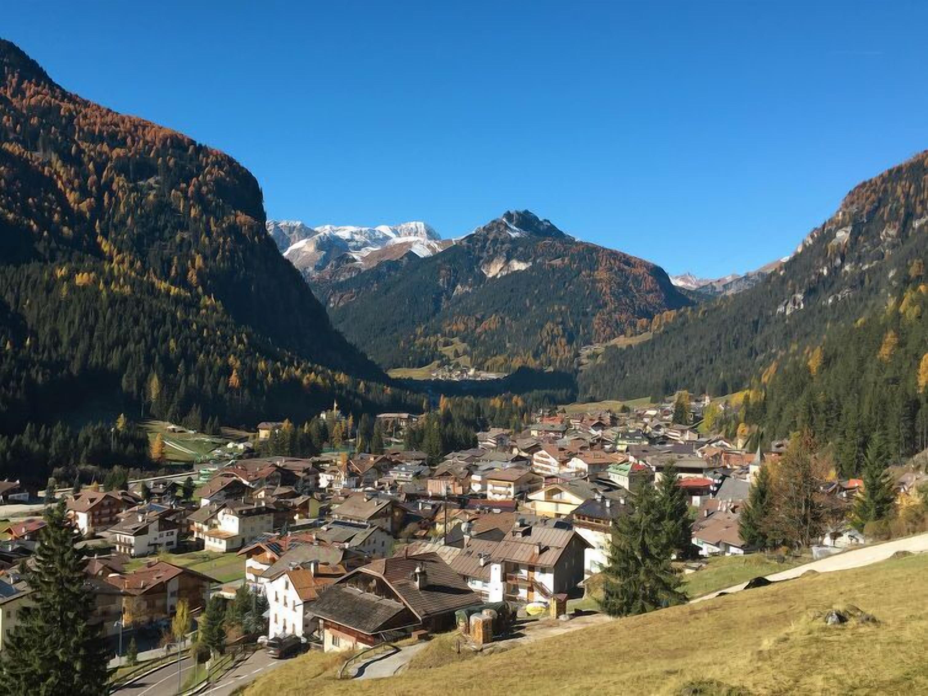 Un village de montagne aux maisons traditionnelles, avec une église et une vue dégagée sur les sommets environnants.