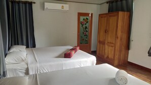 Habitación de hotel con dos camas, un armario de madera, una puerta con diseño floral y un equipo de aire acondicionado en la pared.