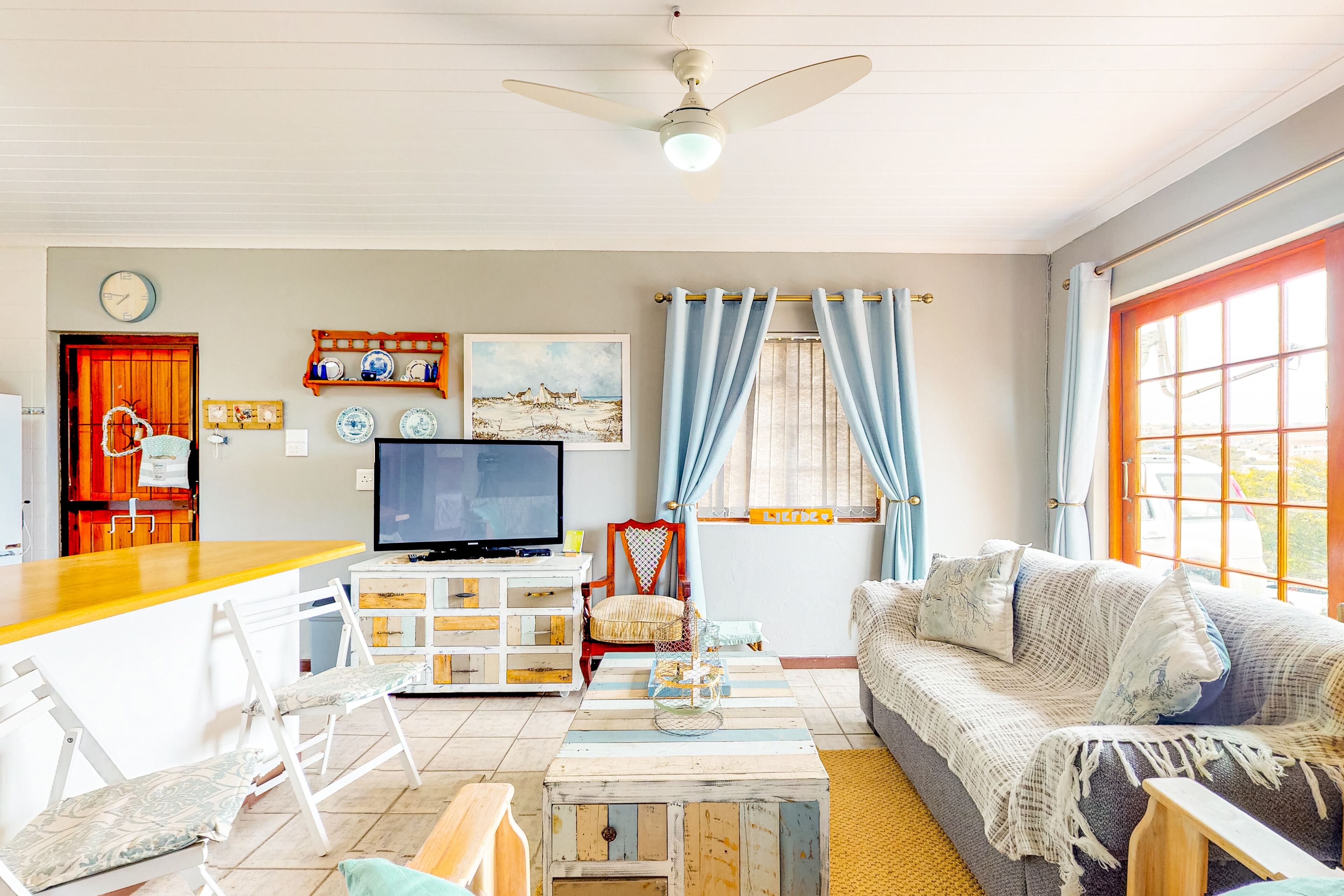 A living room with a television, a sofa, a coffee table, and a dining area with a bar counter.