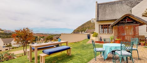 A patio area with a table and chairs, a bench, and a view of the surrounding landscape.