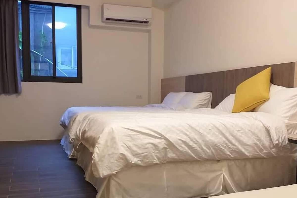 A hotel room with a large bed, a small sofa, and a window with curtains.