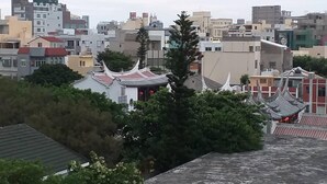 Un edificio tradicional con techo de tejas rojas y paredes blancas, rodeado de edificios modernos.