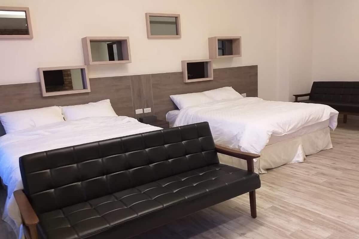 A hotel room with two beds, a black sofa, and built-in shelves with mirrors.