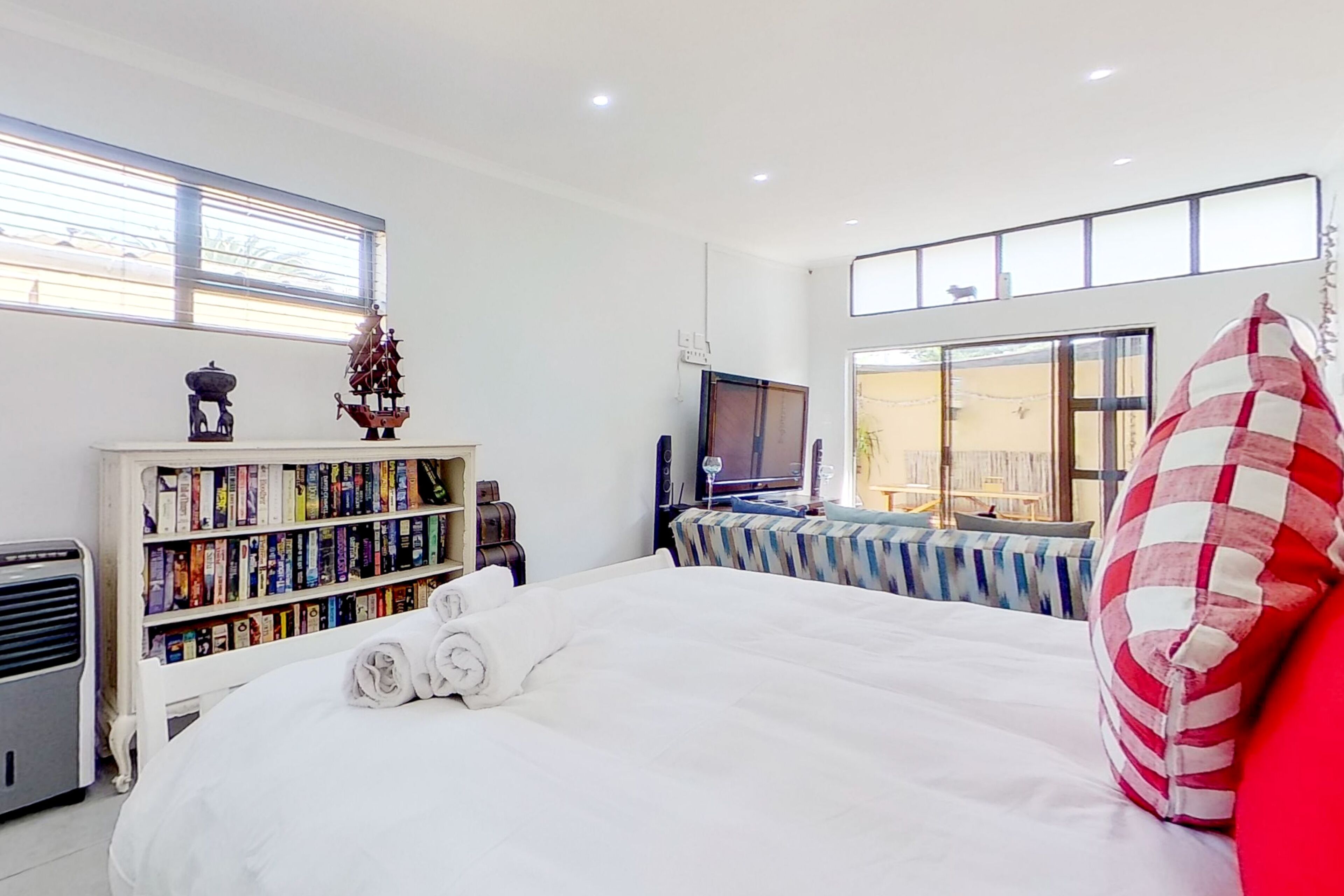 Une chambre d’hôtel moderne avec un grand lit, une bibliothèque, un téléviseur et une fenêtre équipée de stores.