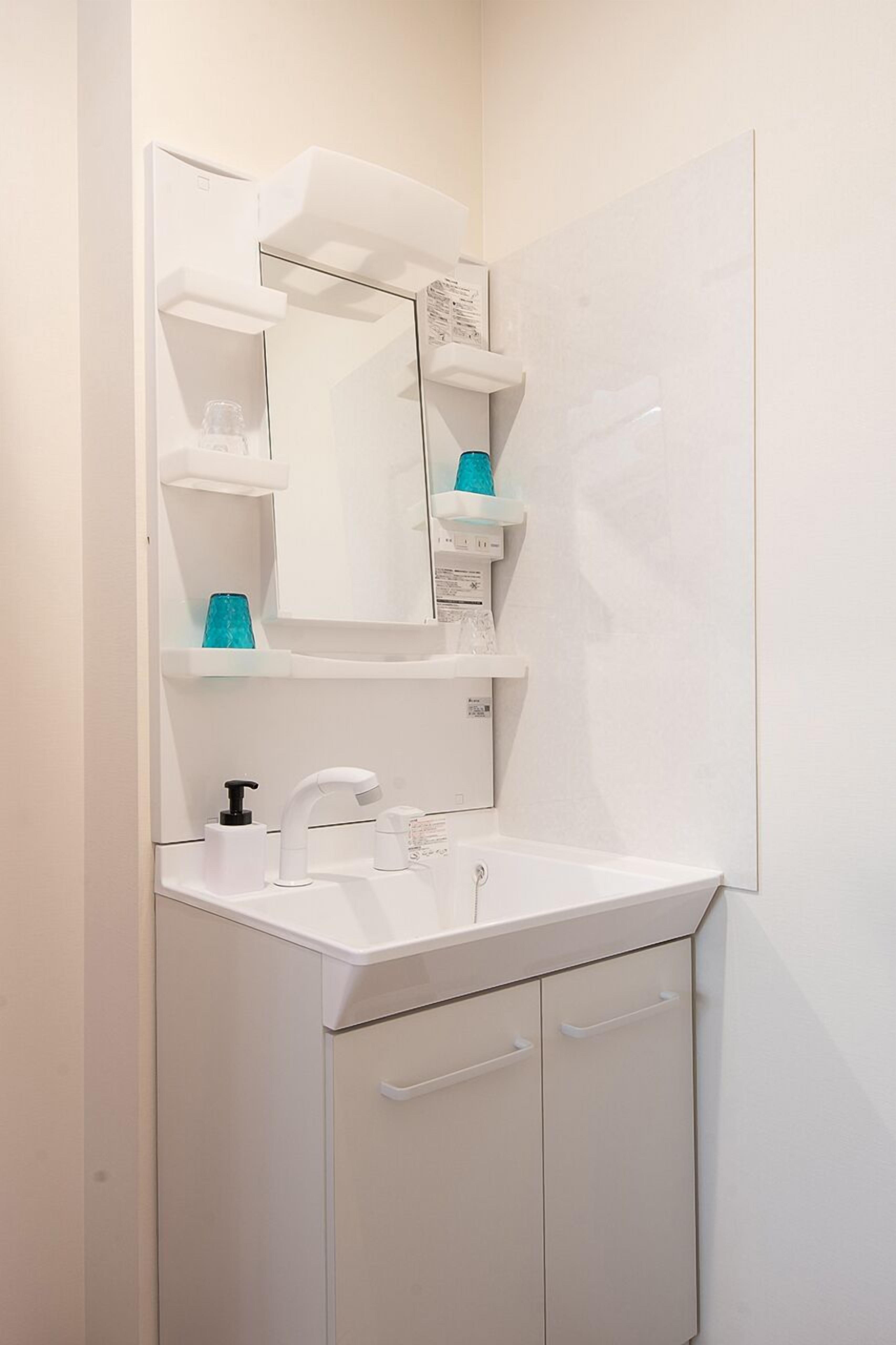 Une salle de bain avec un lavabo blanc, un miroir et un meuble.