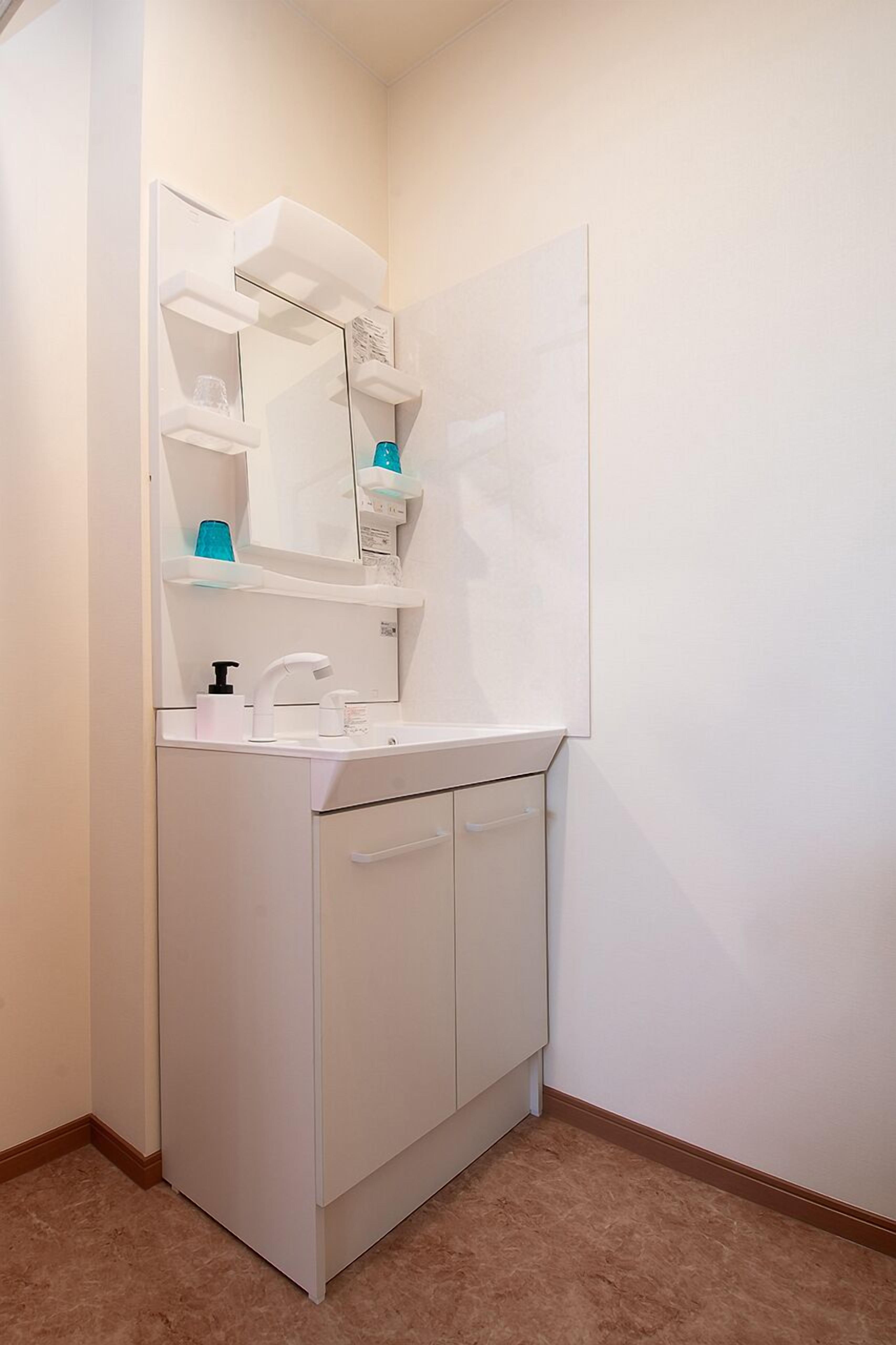 A small, white bathroom with a single sink, a mirror, and a cabinet.