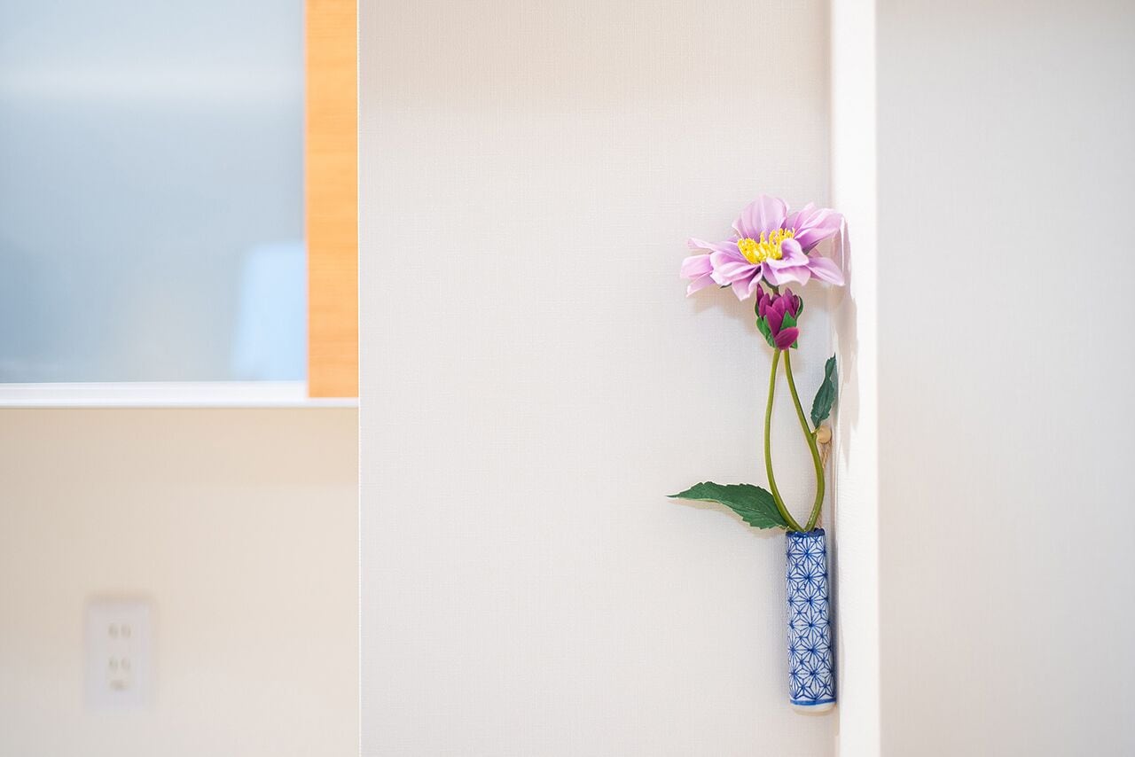 Eine Vase mit einer einzelnen Blume an einer Wand.