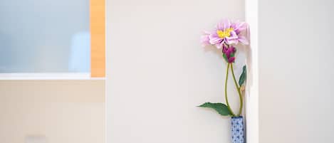 Eine Vase mit einer einzelnen Blume an einer Wand.