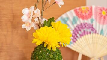 A potted plant with flowers and a decorative fan on a wooden surface.