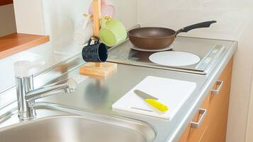 A modern kitchen with a stainless steel sink, wooden cabinets, a stovetop, and a small countertop area.