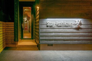 Entrada de un hotel con un letrero que dice "Stay Asahikawa".