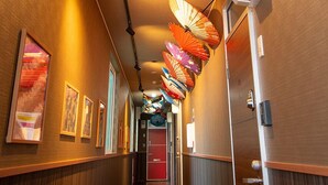 Een hal met houten lambrisering, een vloerbedekking en een reeks kleurrijke paraplu's die aan het plafond hangen.
