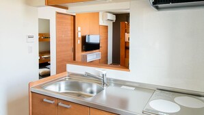 Een kleine keuken met houten kastjes, een roestvrijstalen spoelbak en een ingebouwd fornuis.