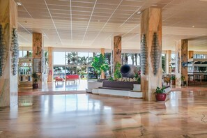 A spacious lobby with marble columns, a central seating area, and large windows offering views of palm trees. - Modern Apartment “Mar Azul Vista Mar” with Sea View, Wi-Fi, Terrace & Shared Pool (Santa Cruz de Tenerife)