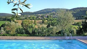A swimming pool with a clear view of a hillside village in the background. - Charming House in Tuscany with Pool & Views (Sovicille)
