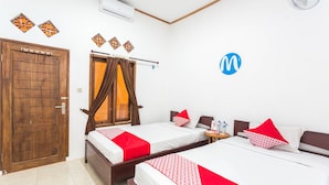 A hotel room with two beds, a wooden door, an air conditioner, and a wall-mounted fan. - OYO 1323 Murni Homestay (Senggigi)