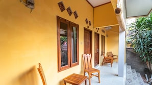 A yellow building with wooden furniture and a tiled floor. - OYO 1323 Murni Homestay (Senggigi)