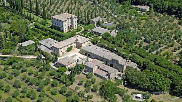 An aerial view of a large estate with multiple buildings, including a prominent tower, surrounded by well-maintained gardens and olive groves. - Charming House in Tuscany with Pool & Views (Sovicille)