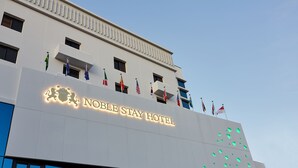 The exterior of the Noble Stay Hotel with multiple flags and illuminated signage. - Noble Stay Hotel (Gwangju)