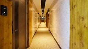 A hotel corridor with wooden walls, a patterned carpet, and a sign indicating room 609. - Noble Stay Hotel (Gwangju)