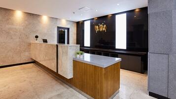 A reception desk with a wooden accent, a laptop, and a small plant.