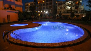 Una piscina con iluminación azul, rodeada por un muro bajo y una escalera metálica.
