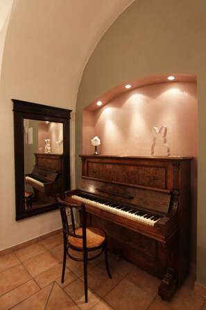 A piano with a mirror above it, a chair in front, and a decorative item on the piano.