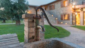 Un robinet extérieur, fixé à une structure en pierre, avec un bâtiment en arrière-plan.