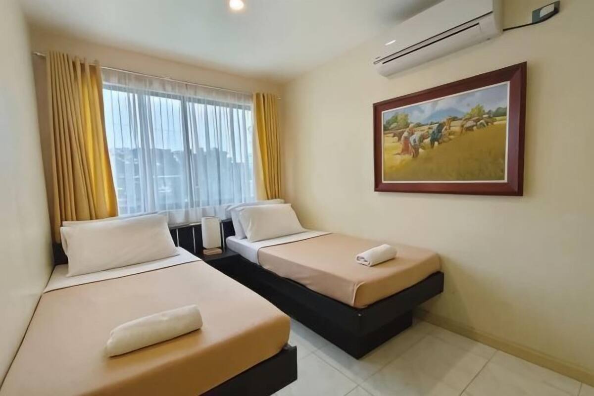 Ein Hotelzimmer mit zwei Betten, einem Bild an der Wand und einer Klimaanlage.