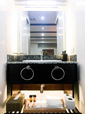 Un baño moderno con tocador negro, dos lavamanos y un espejo.