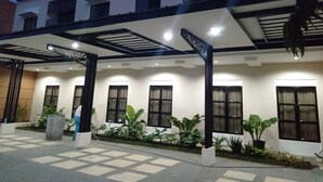 Um edifício moderno com entrada coberta, grandes janelas e plantas em vasos.