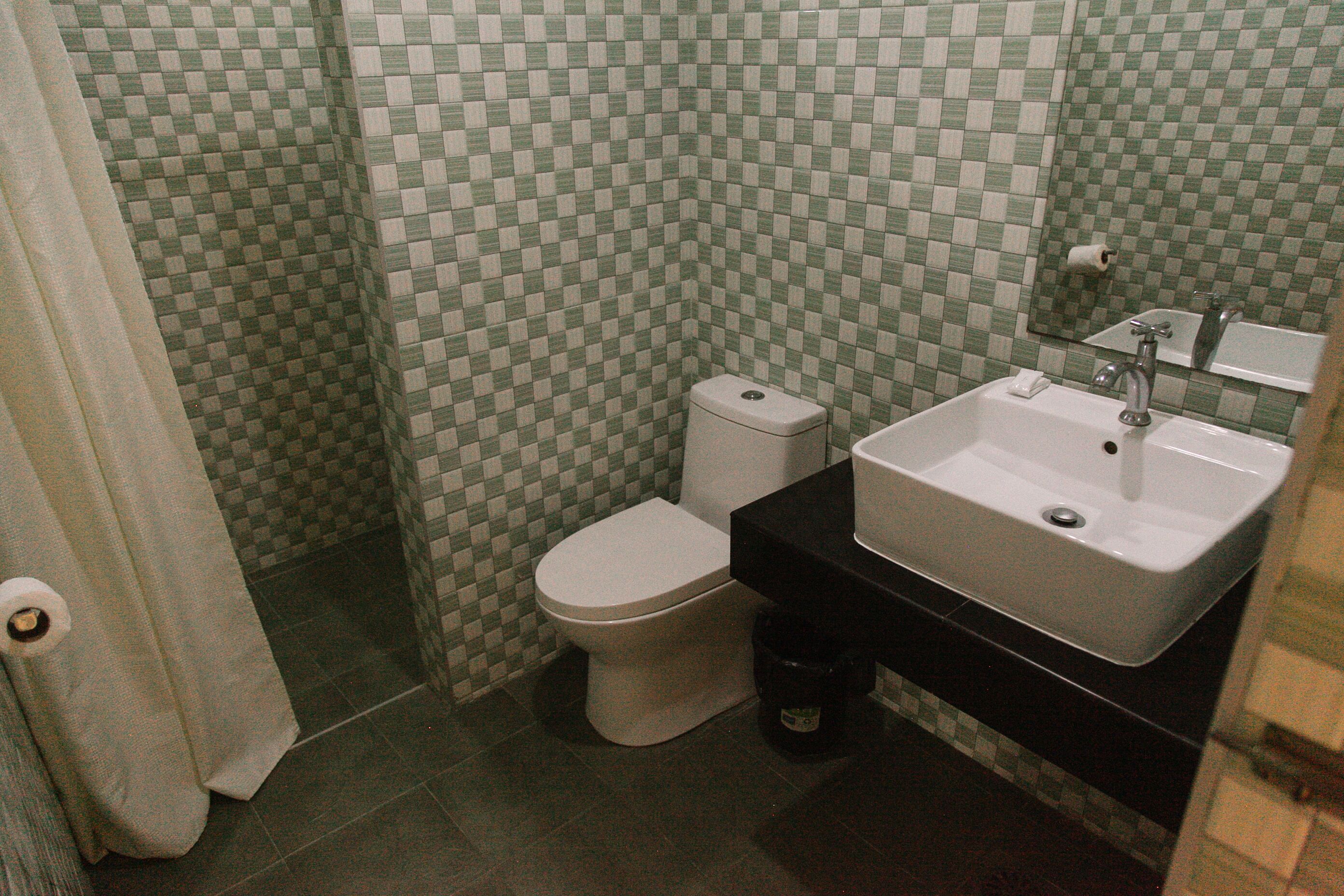 A bathroom with a toilet, sink, and tiled walls.