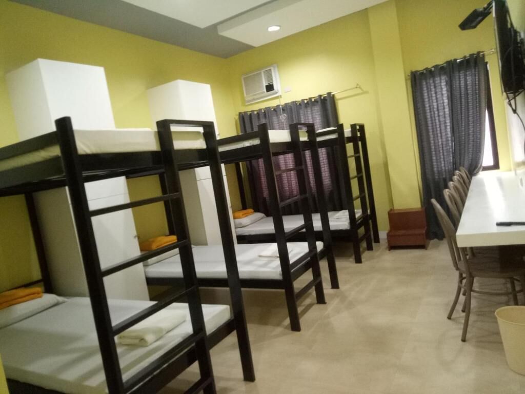 A dormitory room with bunk beds, a desk, and a chair.