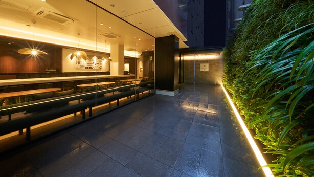A modern indoor space with seating areas, a glass partition, and a green vertical garden. - Hotel Resol Ueno (Tokyo)