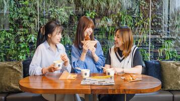 Three people sitting at a round wooden table with a newspaper and a cup of coffee.