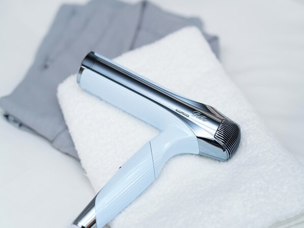 A hair clipper with a chrome finish and a white handle resting on a white towel.