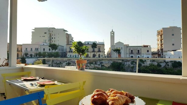 A balcony with a table set for breakfast, featuring croissants and a potted plant. - Santa Marina Bed & Breakfast (Massafra)