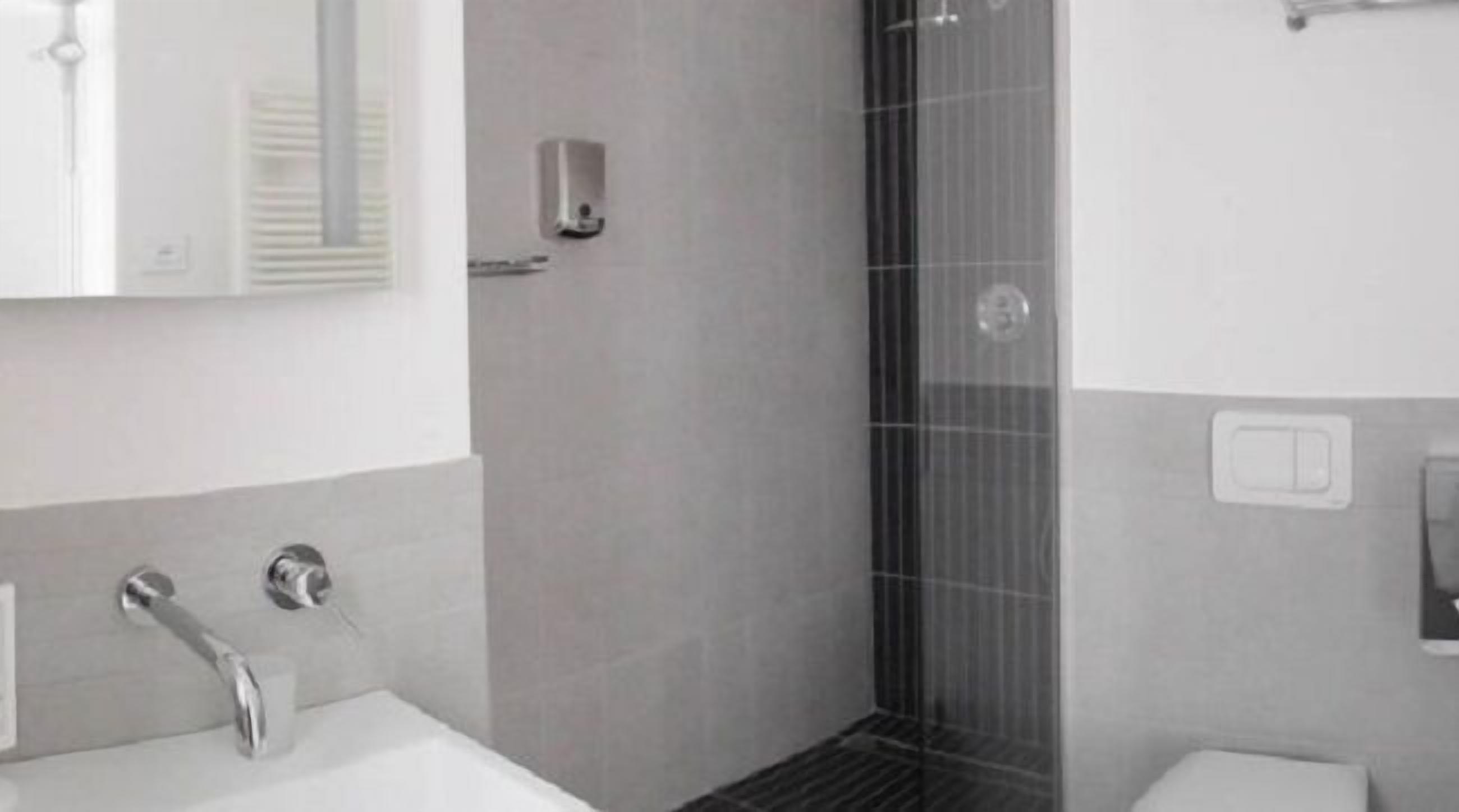 Une salle de bain moderne avec une douche, un lavabo et un miroir.