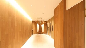 Een moderne hotelgang met houten wanden en een centraal hanglamp.