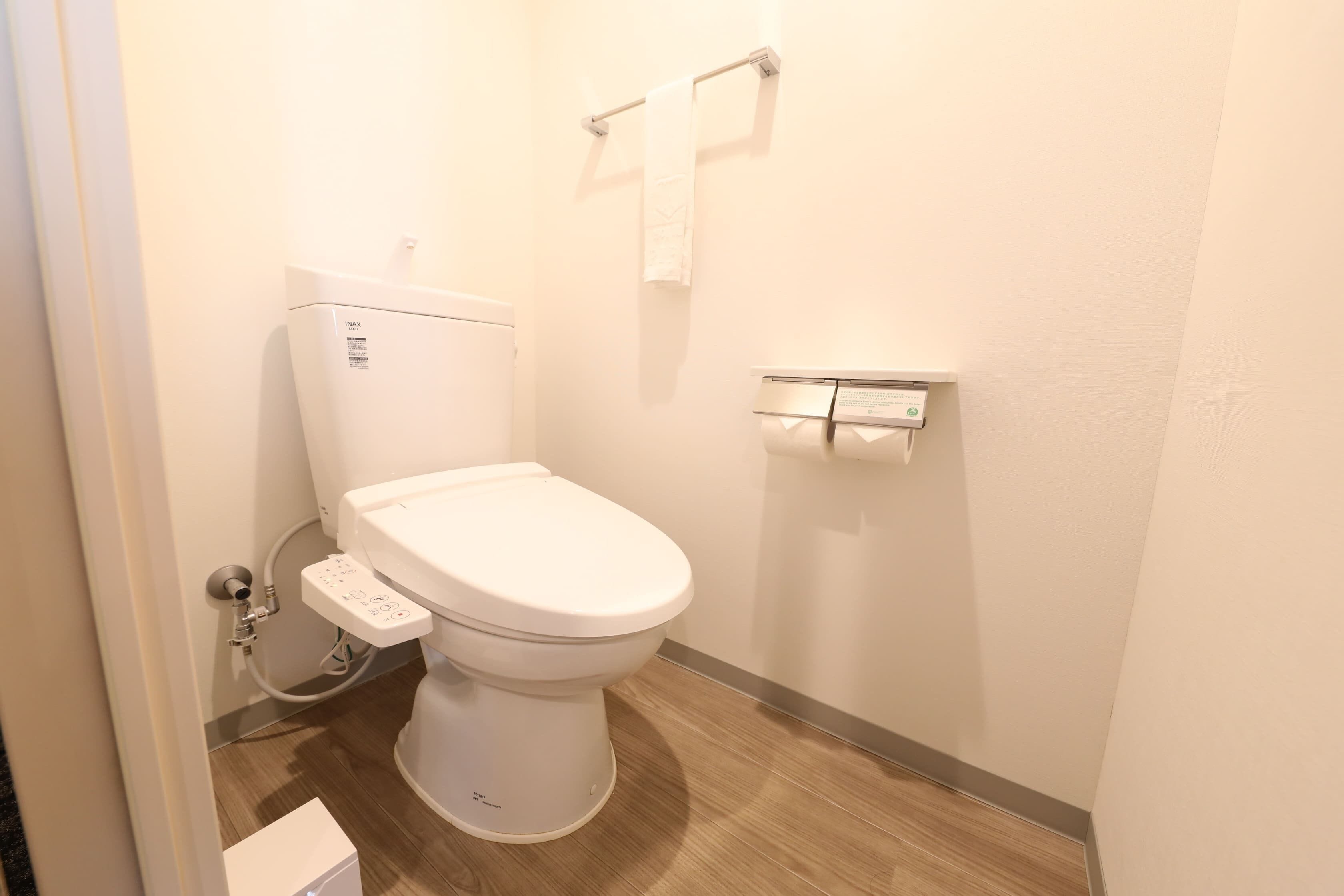 Uma casa de banho moderna com sanita branca, bidé e suporte para papel higiénico.